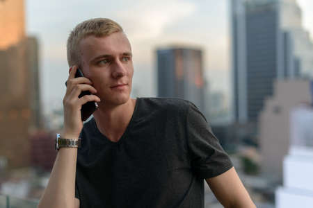 Portrait of young man with blond hair against view of the cityの写真素材