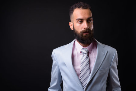 Young handsome Persian businessman with dreadlocks against black background