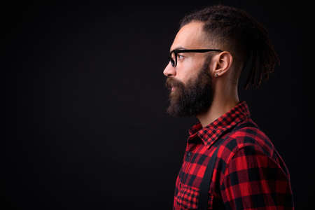 Young handsome Persian man with dreadlocks against black backgroundの写真素材