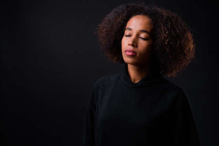 Young beautiful African woman with Afro hair against black backgroundの写真素材