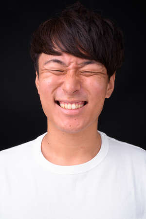 Young handsome Asian man against black backgroundの写真素材