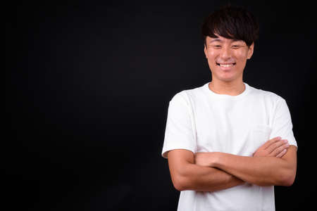 Young handsome Asian man against black backgroundの写真素材