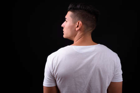 Young handsome multi ethnic man against black backgroundの写真素材