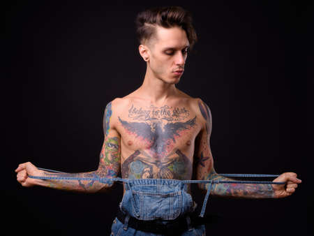 Young handsome rebellious man shirtless against black backgroundの写真素材