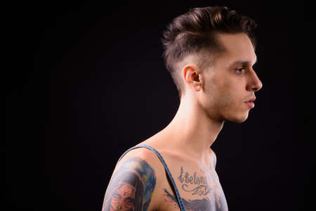 Young handsome rebellious man shirtless against black backgroundの写真素材