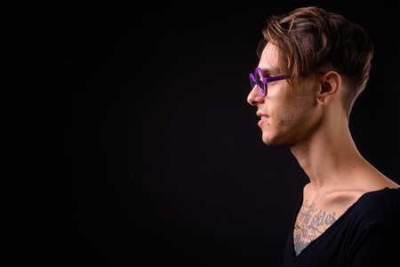 Young handsome rebellious man against black backgroundの写真素材