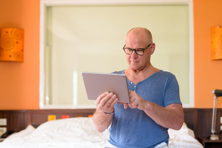 Senior handsome Scandinavian man relaxing inside the bedroomの写真素材
