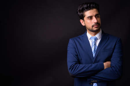 Young handsome bearded Persian businessman against black backgroundの写真素材