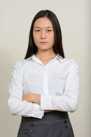 Portrait of young beautiful Asian businesswoman against white backgroundの写真素材