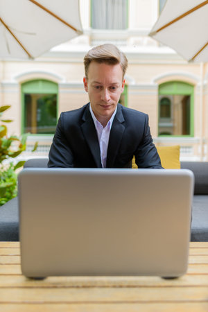 Young handsome blond businessman using laptop at the coffee shop
