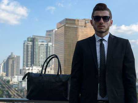 Handsome bearded Hispanic businessman against view of the cityの写真素材