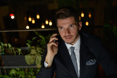 Handsome bearded Hispanic businessman relaxing at the coffee shop at nightの写真素材