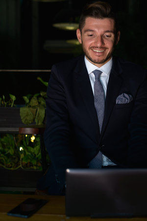 Handsome bearded Hispanic businessman relaxing at the coffee shop at night