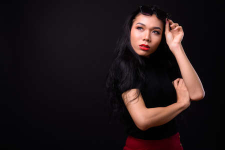 Young beautiful Asian transgender businesswoman against black backgroundの写真素材