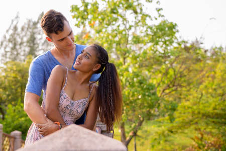 Portrait of young multi ethnic couple relaxing together at the parkの写真素材