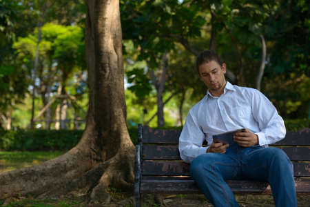 Handsome bearded businessman with long hair at the parkの写真素材
