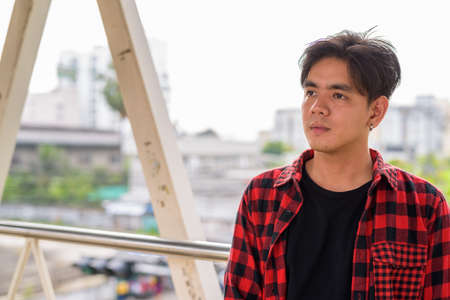 Young handsome Asian hipster man at footbridge in the cityの写真素材