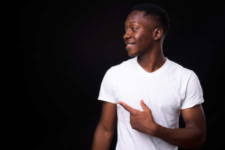 Happy young handsome African man against black backgroundの写真素材