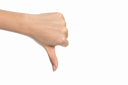 Portrait of hand giving thumbs down against white background