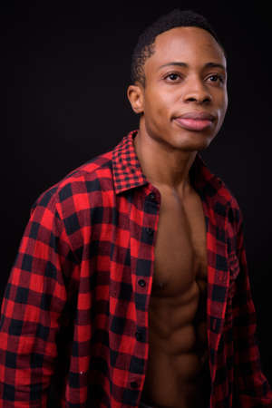 Young handsome African hipster man against black backgroundの写真素材