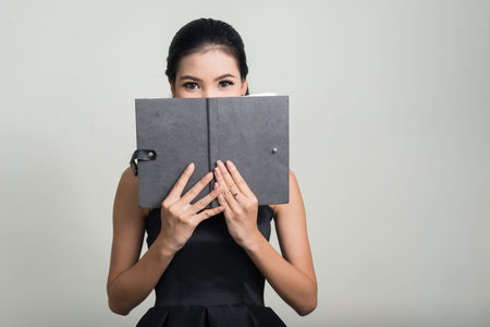 Portrait of young beautiful Asian businesswoman with book