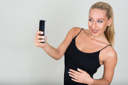 Portrait of young beautiful blonde woman taking selfie