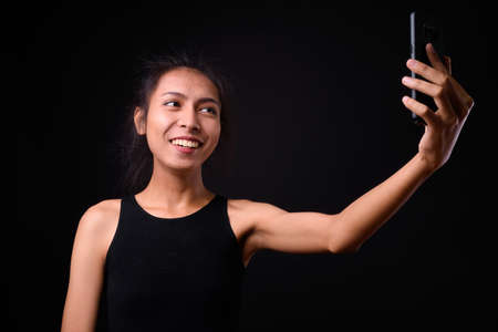 Portrait of happy young beautiful Asian transgender woman taking selfieの写真素材