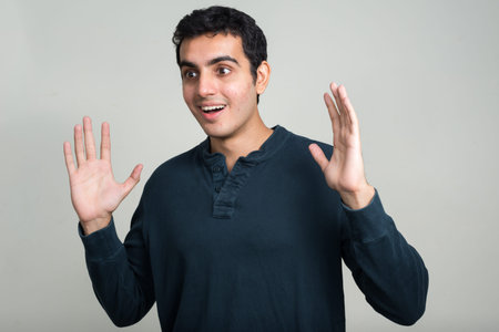 Portrait of happy young handsome Indian man looking surprised