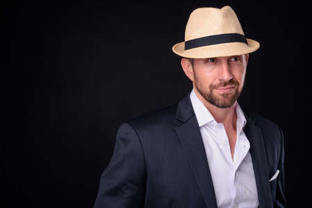 Portrait of handsome bearded businessman in suit wearing hatの写真素材