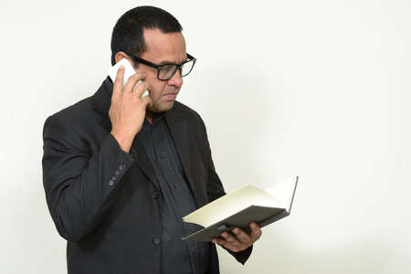 Portrait of Indian businessman in suit with book and phoneの写真素材
