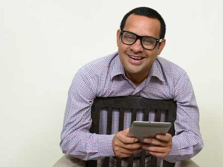 Portrait of happy overweight Indian businessman with digital tabletの写真素材