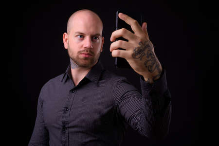 Portrait of handsome bald bearded businessman taking selfieの写真素材