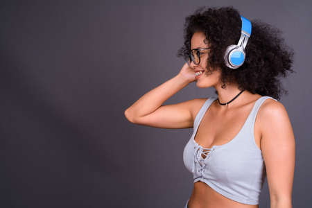Happy young beautiful African woman with Afro hair listening to musicの写真素材