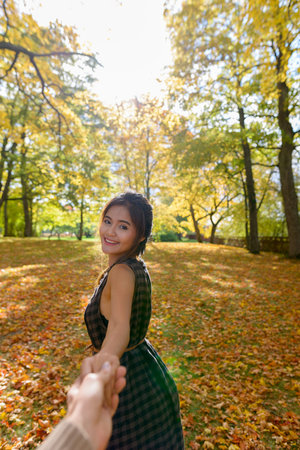 Young happy Asian woman smiling while leading man in the forest holding hands