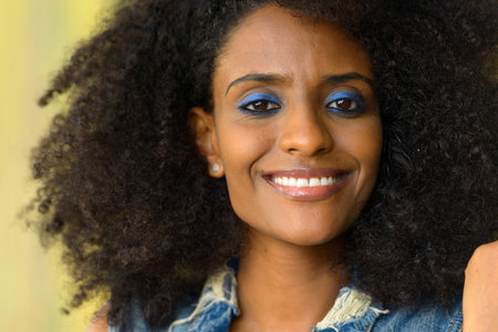 Happy young beautiful African woman with Afro hair outdoors