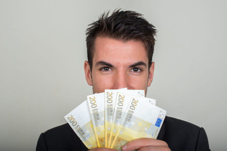 Portrait of young handsome Hispanic businessman in suit