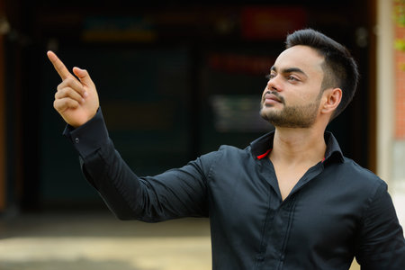 Young handsome bearded Indian businessman in the city
