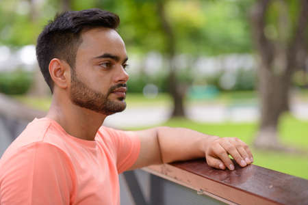 Young handsome bearded Indian man at the parkの写真素材