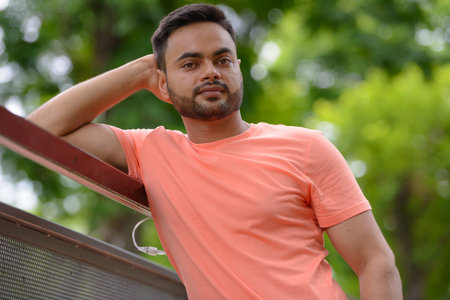 Young handsome bearded Indian man at the parkの写真素材