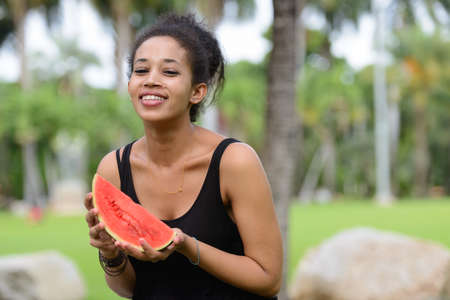 Portrait of happy young beautiful African woman at the parkの写真素材