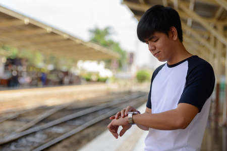 Young handsome Asian tourist man at the railway stationの写真素材