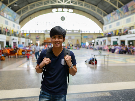 Happy young handsome Asian tourist man at the railway station
