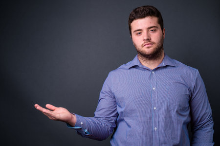 Portrait of young handsome overweight bearded businessman