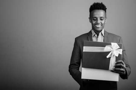 Young handsome African businessman holding gift boxの写真素材