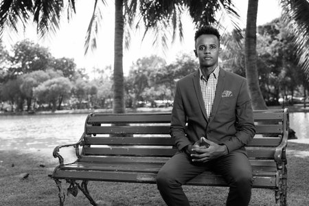 Young handsome African businessman relaxing at the park