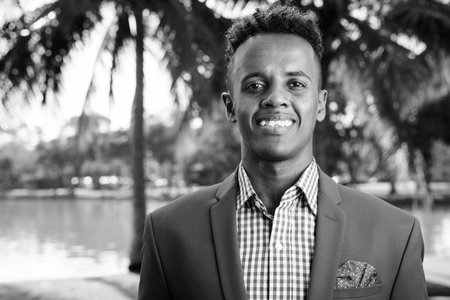 Young handsome African businessman relaxing at the park