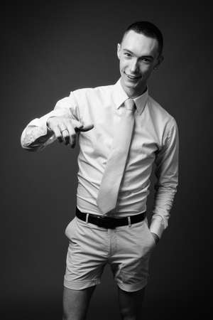 Young handsome androgynous businessman against gray backgroundの写真素材