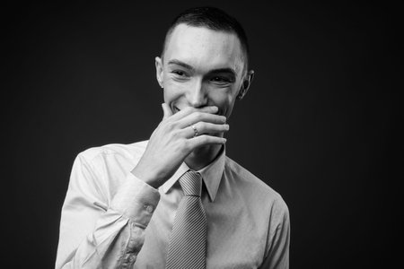 Young handsome androgynous businessman against gray background