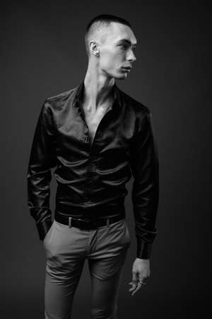 Young handsome androgynous businessman against gray backgroundの写真素材