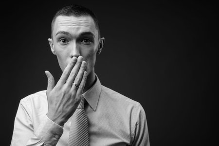 Young handsome androgynous businessman against gray background